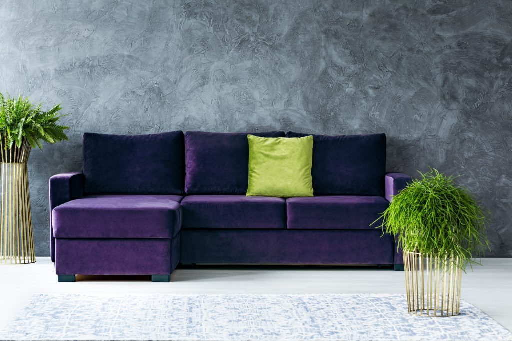 lila Sofa mit grünem Kissen